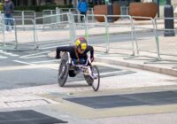 A dedicated athlete competes in a marathon using a racing wheelchair on city streets.